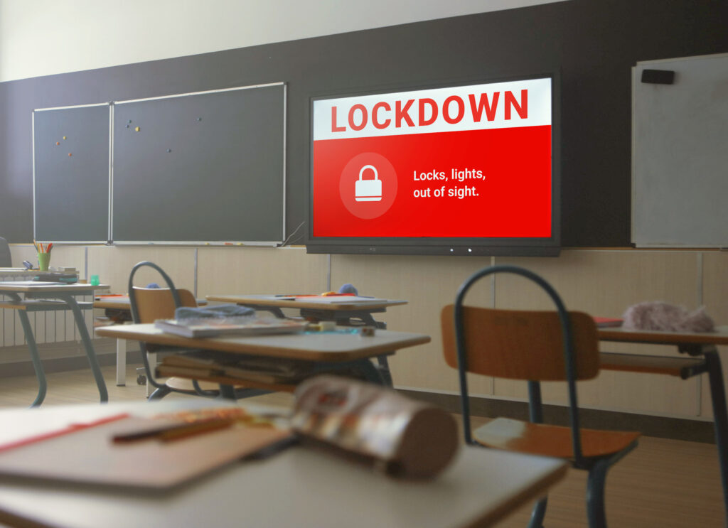 Classroom with emergency lockdown notification displayed on screen.