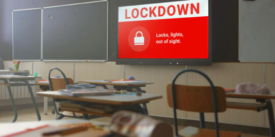 Classroom with emergency lockdown notification displayed on screen.
