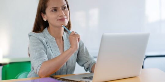 Female teacher thinking in front of the computer in the classroom