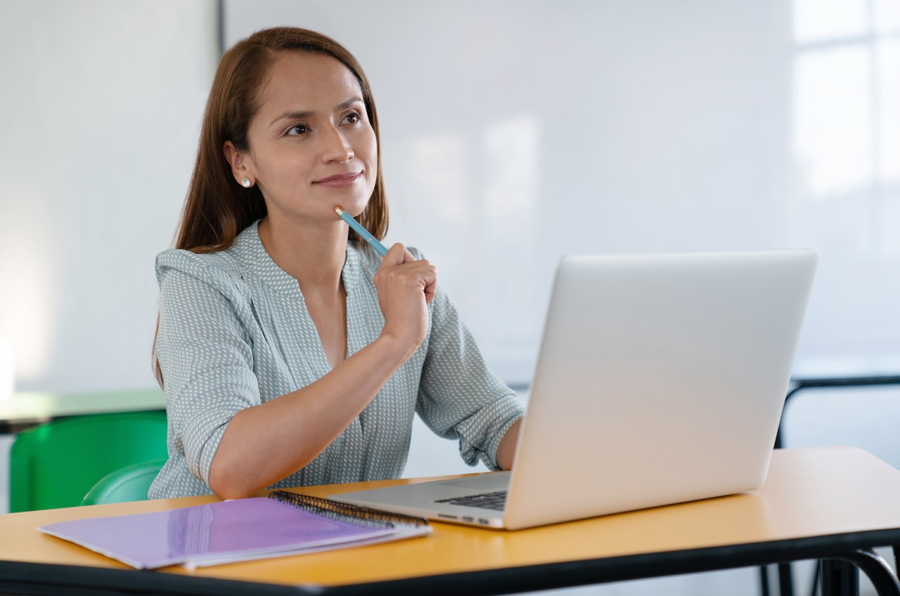 Female teacher thinking in front of the computer in the classroom