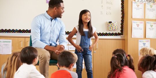 Schoolgirl at front of elementary class with teacher