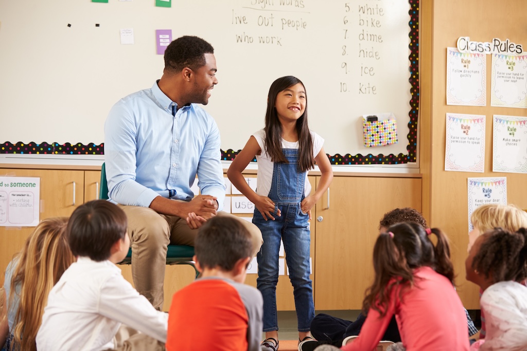 Schoolgirl at front of elementary class with teacher